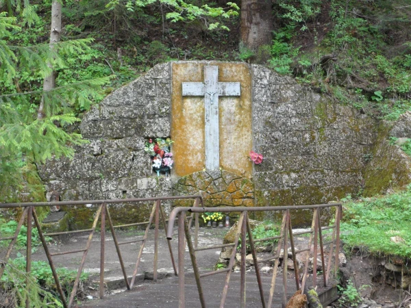 Крест выбит в горе в чаще леса.