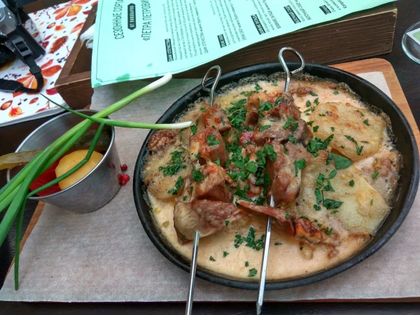 Шашлычки из телячьего языка, запеченные под сырным соусом, на картофельном гратене с грецкими орехами и домашними соленьями