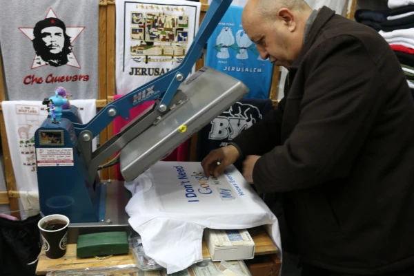 Дочери делают футболку по индивидуальному заказу в магазине на Виа Долороза